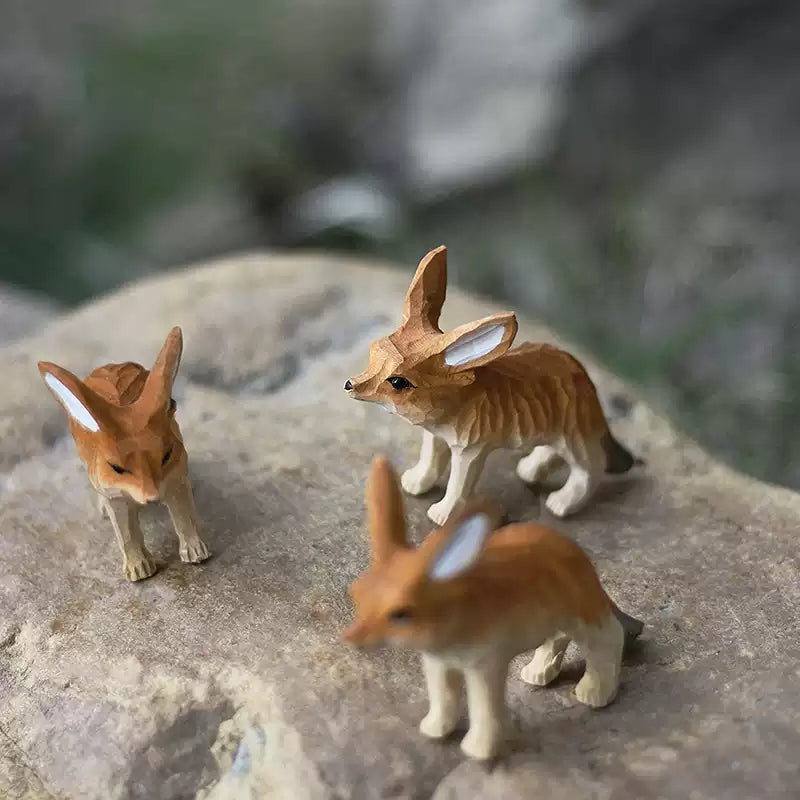 Three fennec fox figurines grouped on rock