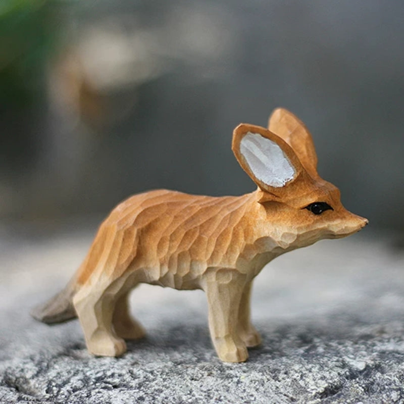 Side view of fennec fox wooden figurine on rock