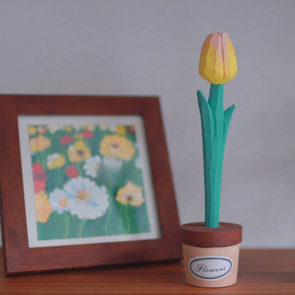Yellow-pink wooden tulip pen in a pot holder with a framed floral painting behind it.