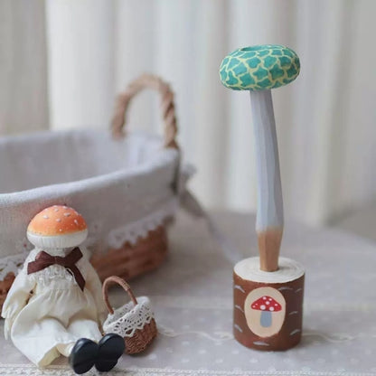 Green mushroom pen in a wooden holder beside a seated mushroom figurine with a small basket.