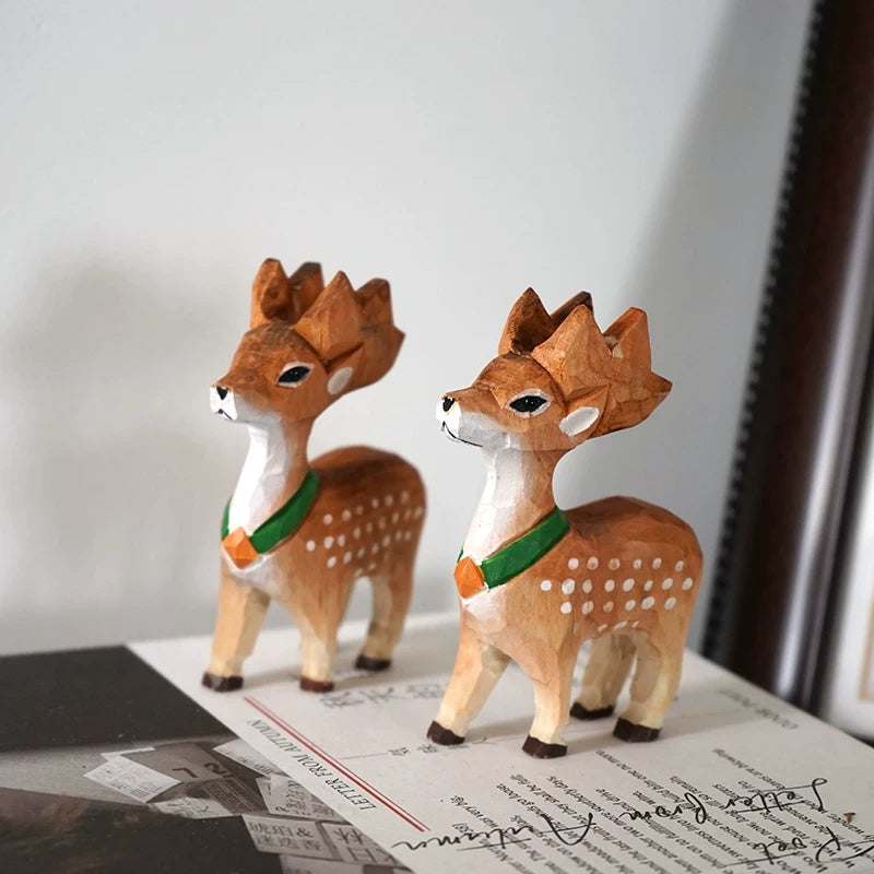 Two green-scarf deer figurines displayed together on a tabletop