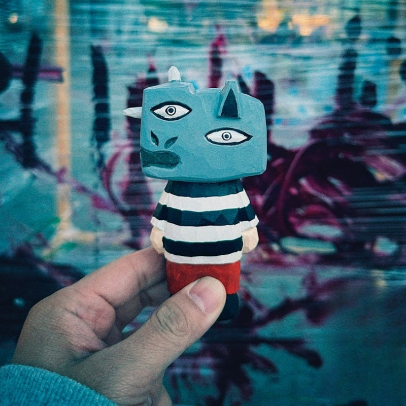 Hand holding wooden figure with a surreal urban graffiti backdrop in blue and purple tones.