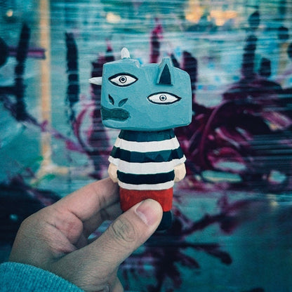 Hand holding wooden figure with a surreal urban graffiti backdrop in blue and purple tones.