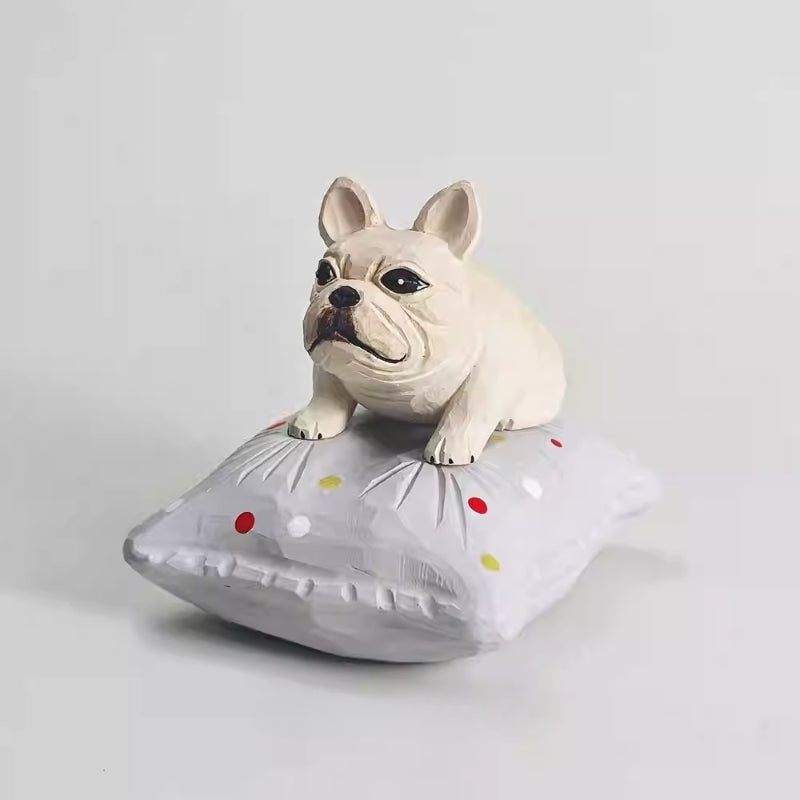 Hand-carved wooden French bulldog figurine resting on a gray dotted cushion