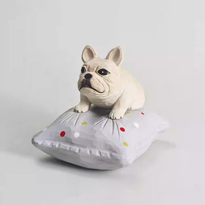 Hand-carved wooden French bulldog figurine resting on a gray dotted cushion