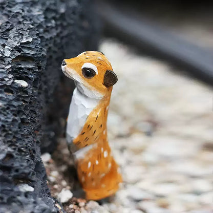 Hand-carved meerkat wooden figurine in rocky crevice