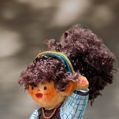 Close-up of wood doll keychain with coffee cup detail, showing hand-carved face and soft yarn hair