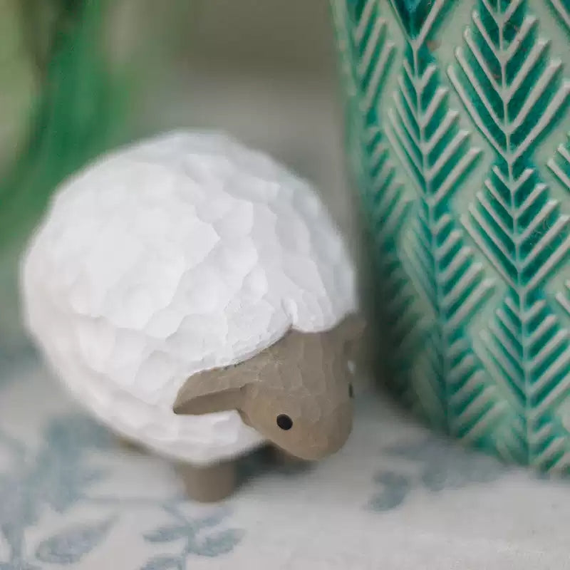 Close-up of lamb figurine with bowed head and carved wool texture