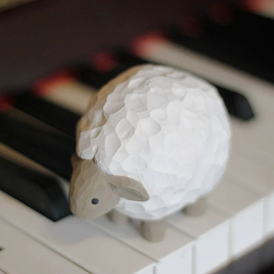 Lamb wooden figurine resting on piano keys