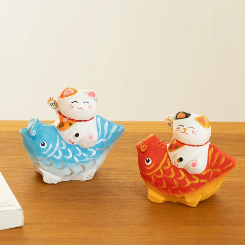 Lucky cat figurine on red and blue koi fish