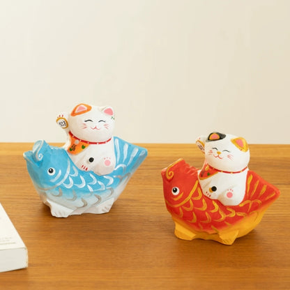 Lucky cat figurine on red and blue koi fish
