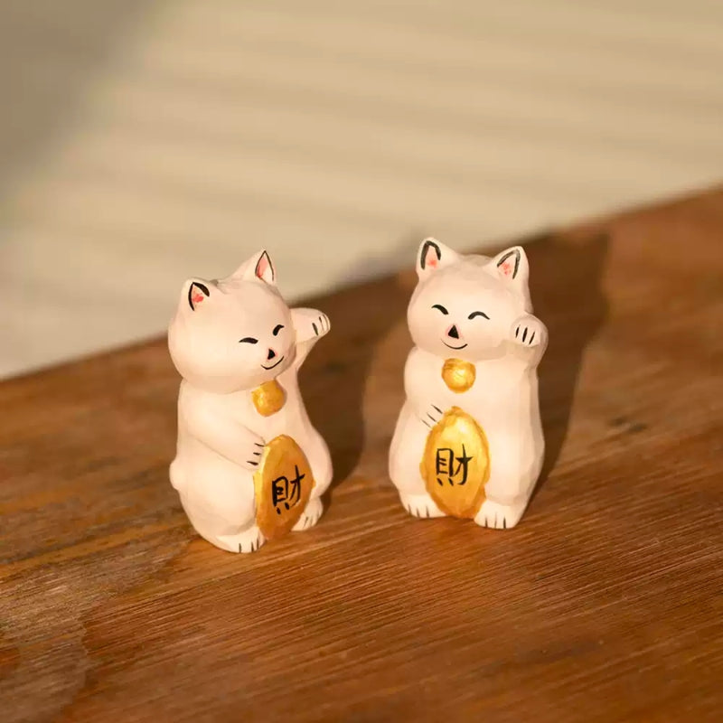 Pair of maneki neko figurines on wooden surface