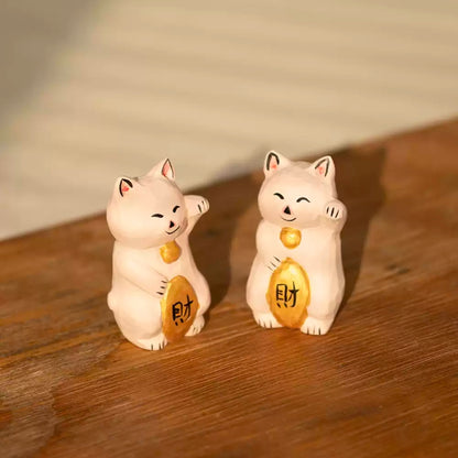 Pair of maneki neko figurines on wooden surface