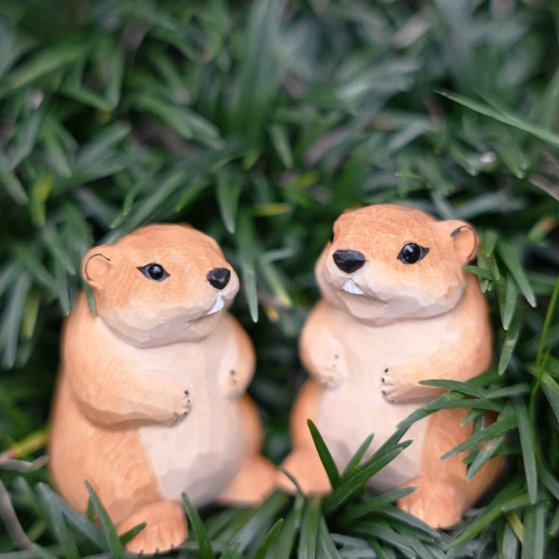 Pair of marmot figurines facing each other in grass