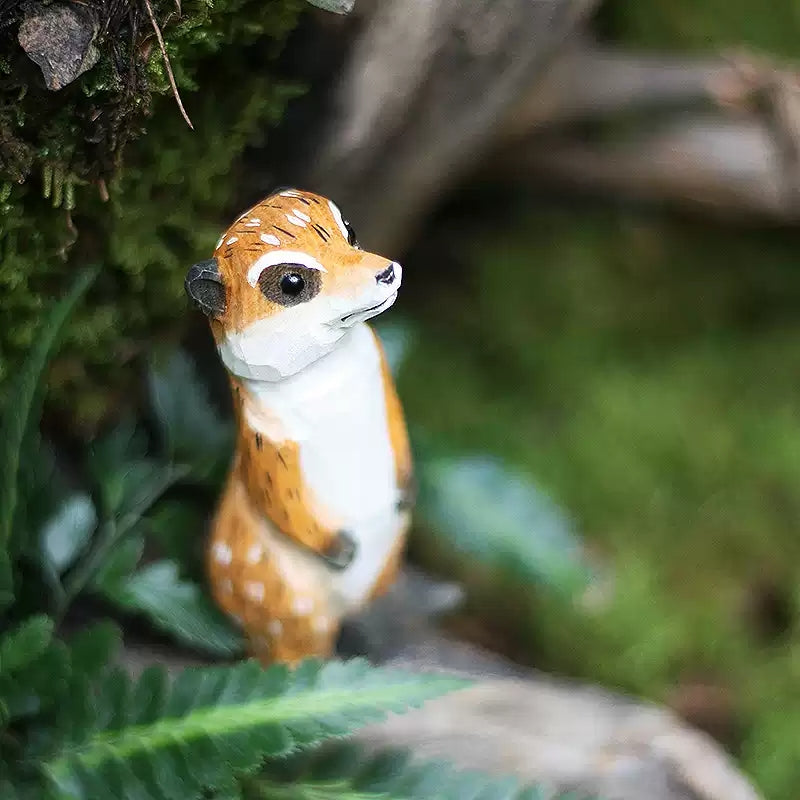 Meerkat figurine among moss and fern