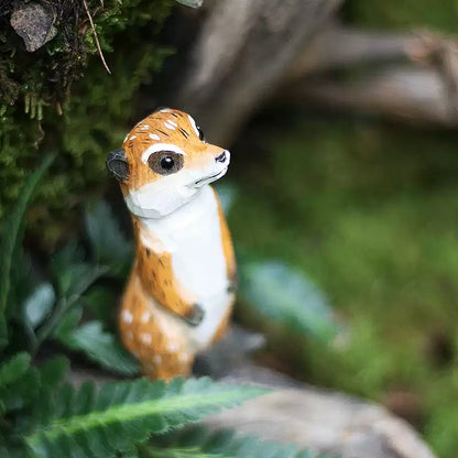 Meerkat figurine among moss and fern