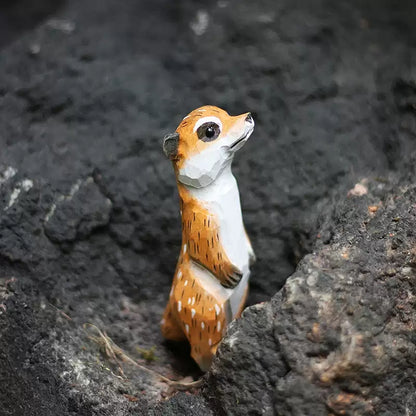 Meerkat figurine standing beside dark volcanic rock
