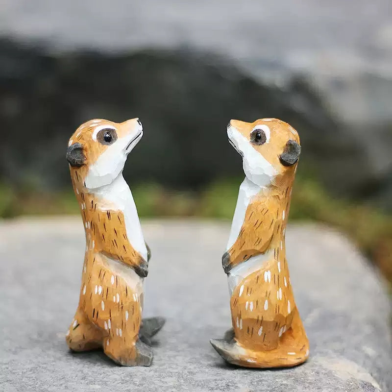 Pair of meerkat figurines facing each other on rock