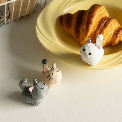 Three mini cat figurines beside croissant