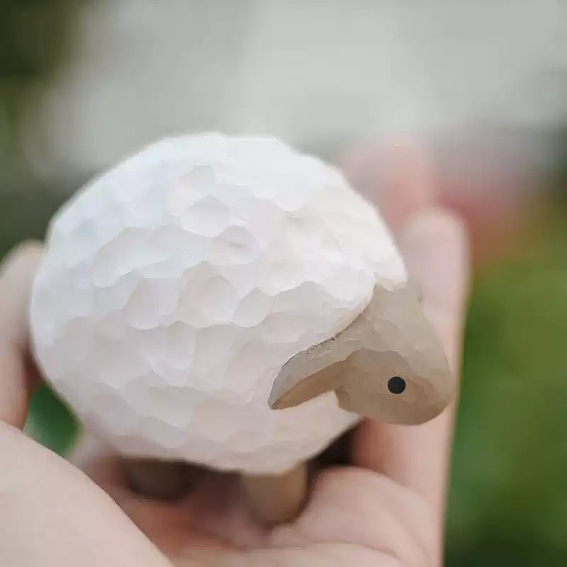 Miniature lamb figurine held in hand for scale