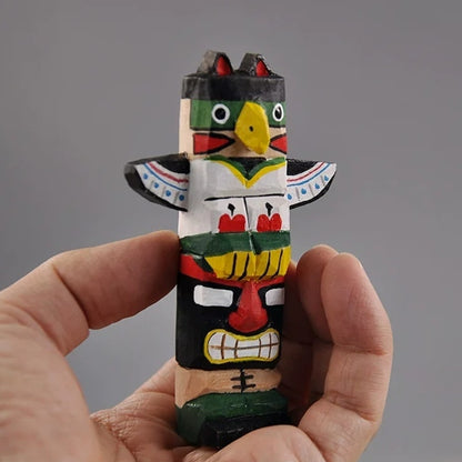 Hand carved totem pole figurine held in hand for scale