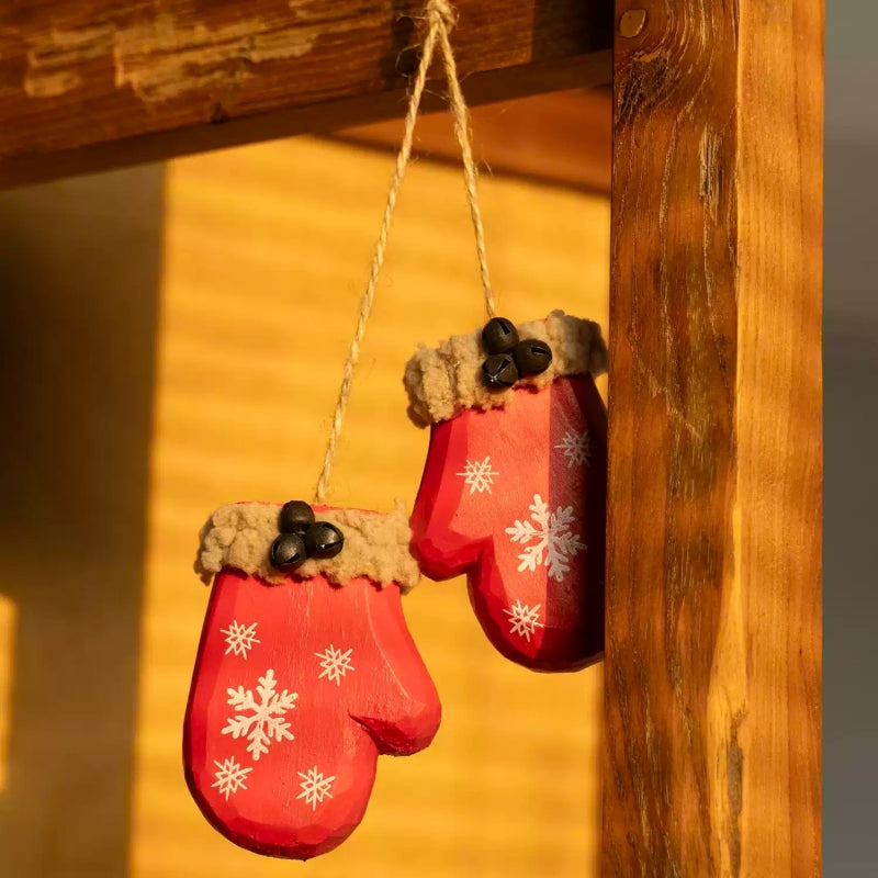 Two red mitten ornaments joined by twine and hanging from a wooden frame