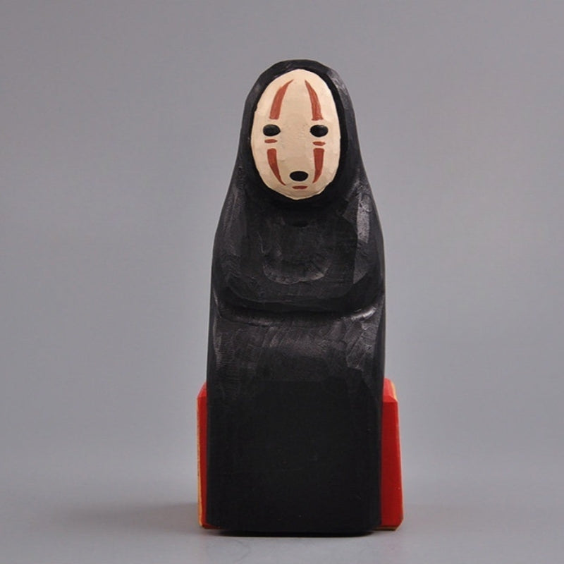 Front view of No Face Figure wooden collectible sitting on a red and wood-tone block.