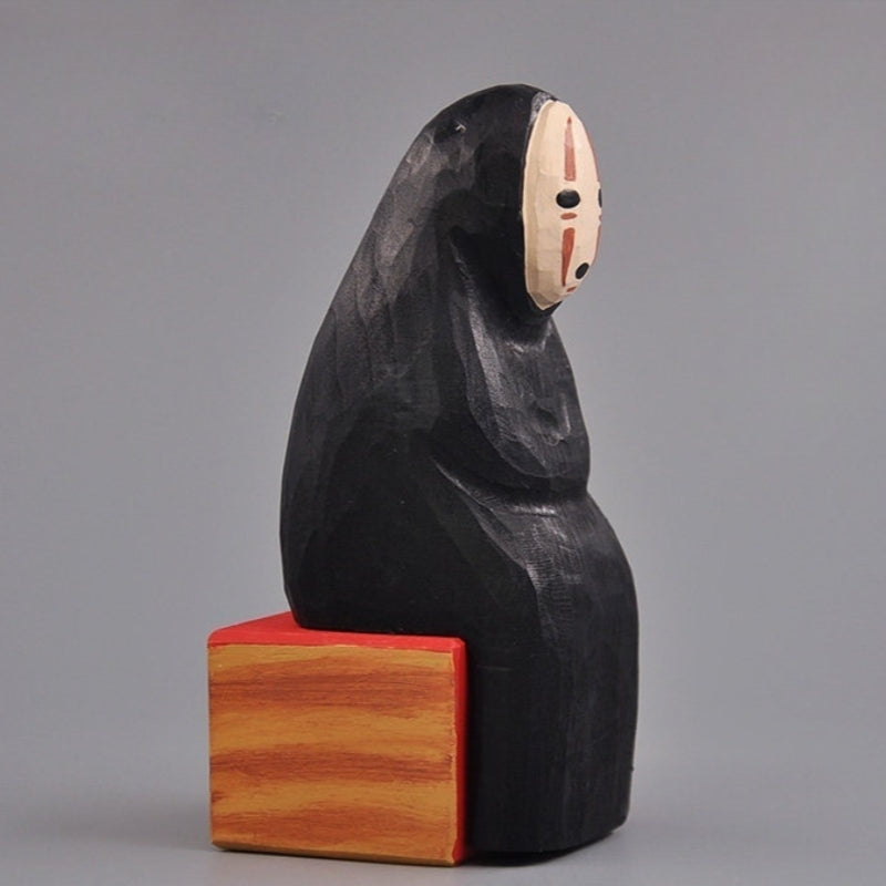 Side profile of the No Face Figure hand-carved sculpture in natural lighting.