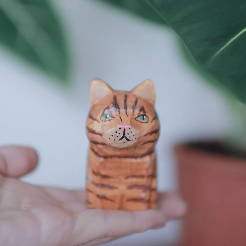 Orange cat wooden figurine in hand