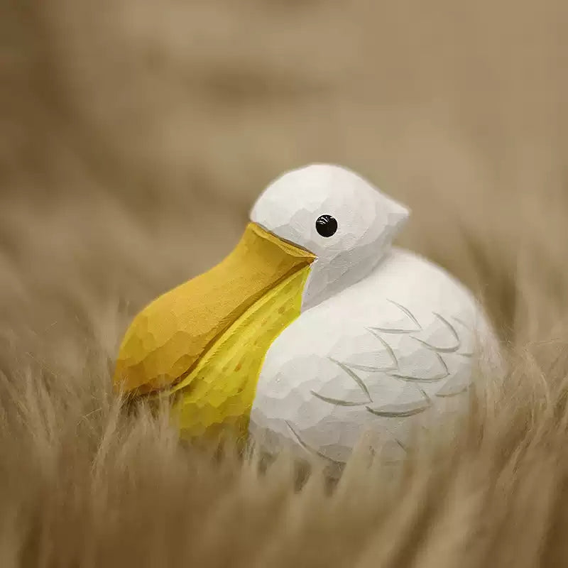 White pelican figurine displayed among dried grass