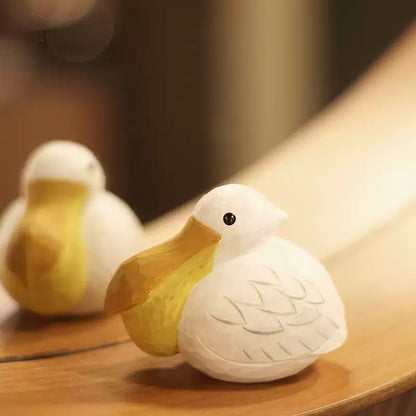 Two pelican figurines displayed together on a wooden surface