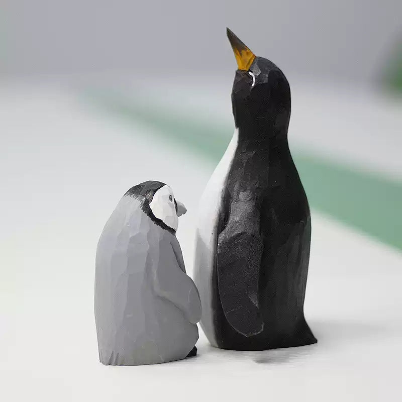 Penguin figurines with a black-and-white father and a gray chick standing close together