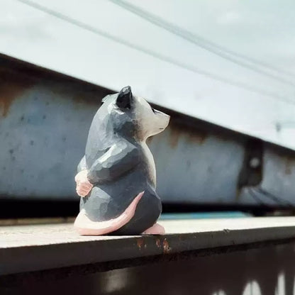 Possum figurine with pink hands held behind its back and a curved pink tail
