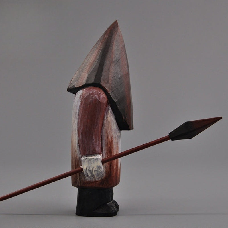 Profile shot of the Pyramid Head hand-carved statue holding a spear, displaying the figure’s side silhouette.