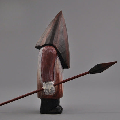 Profile shot of the Pyramid Head hand-carved statue holding a spear, displaying the figure’s side silhouette.