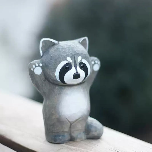 Raccoon figurine with both arms raised on wooden ledge