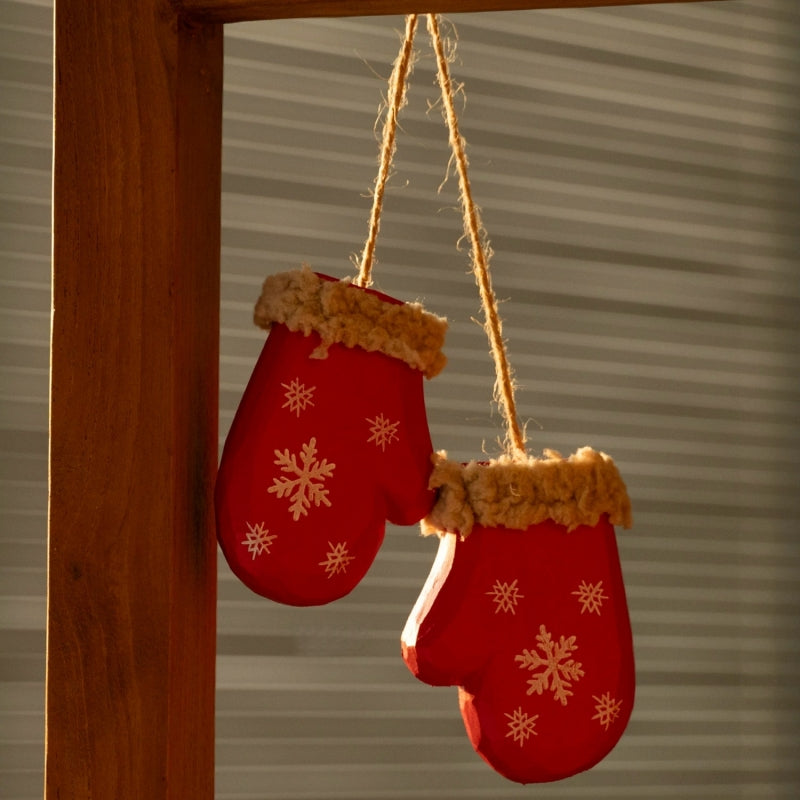 Two red wooden mittens hanging at different heights from twine against window blinds