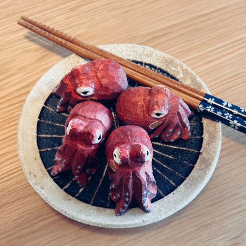 Four red octopus figurines on ceramic plate