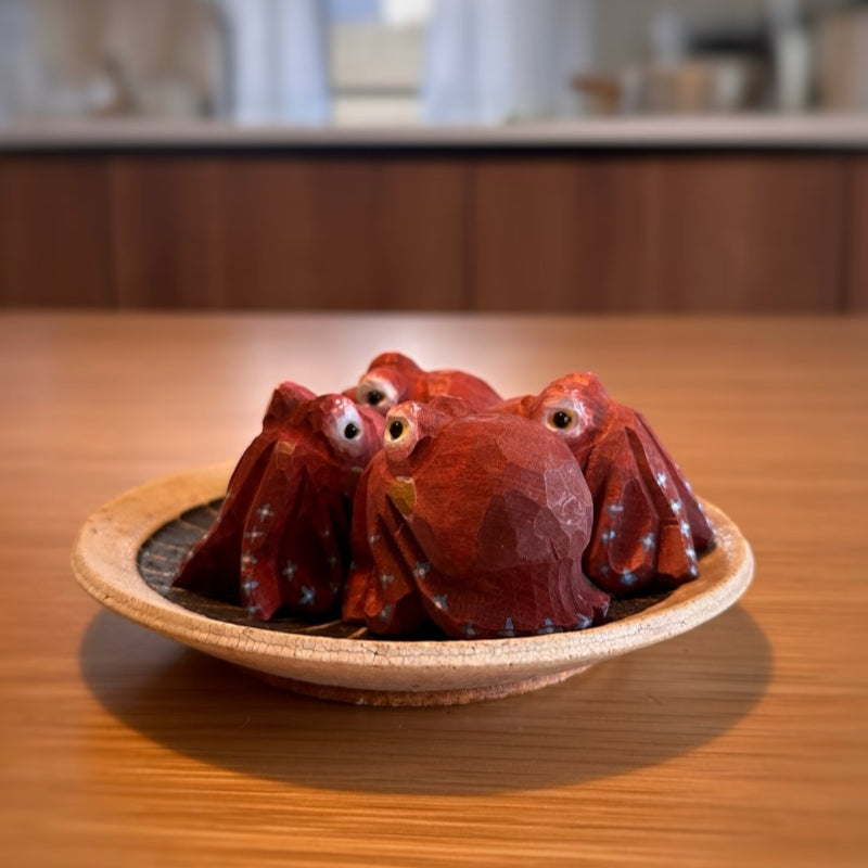 Red octopus wood sculptures in wooden dish