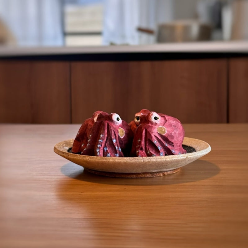 Two red octopus wood sculptures facing each other