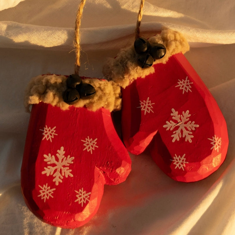 Pair of red wooden mitten ornaments with white snowflakes, fluffy tan cuffs, and black bells