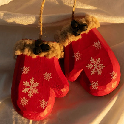 Pair of red wooden mitten ornaments with white snowflakes, fluffy tan cuffs, and black bells