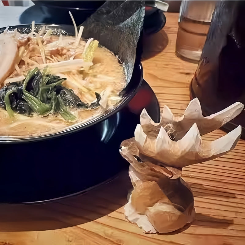 Reindeer figurines Christmas style – small antlered wooden reindeer placed beside ramen in cozy restaurant setting.