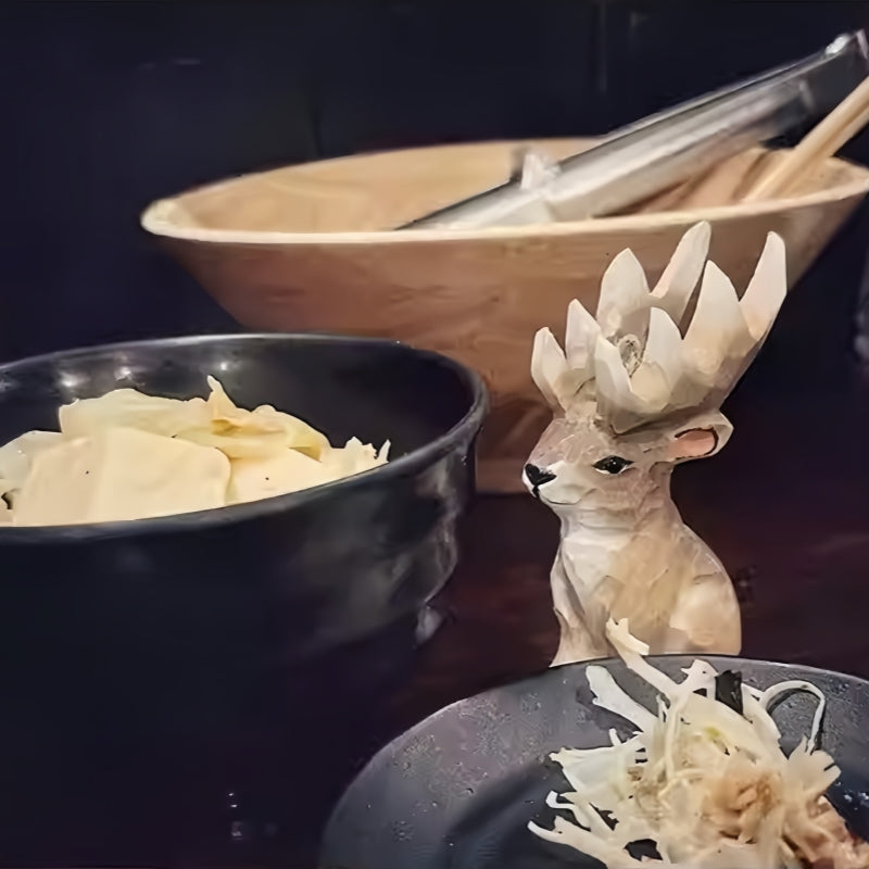 Hand-carved Christmas reindeer figurine with large antlers sitting next to traditional noodle dishes.