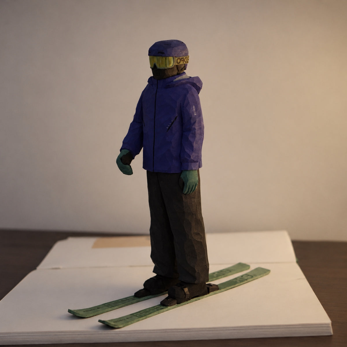 Three-quarter view of a wooden ski figurine standing on green skis