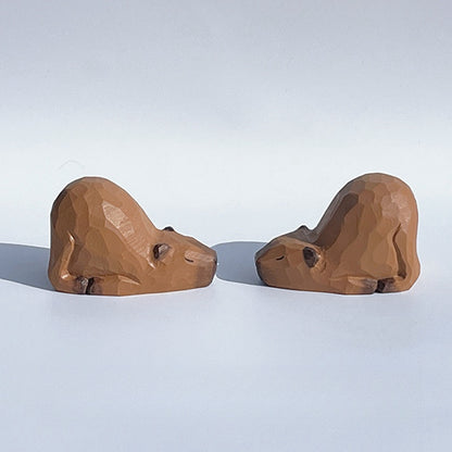 Two capybara figurines, hand-painted wooden statues.
