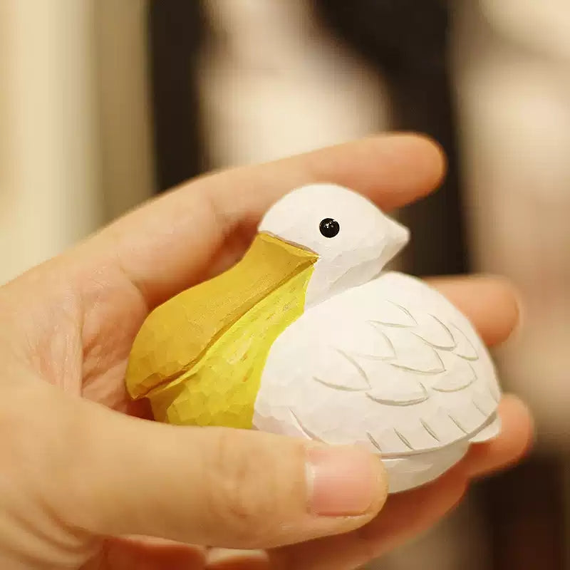 Small pelican figurine held in one hand to show its scale