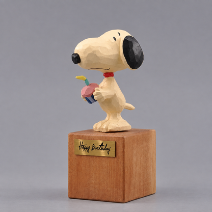 Three-quarter view of Snoopy holding the cupcake on the wooden Happy Birthday display block