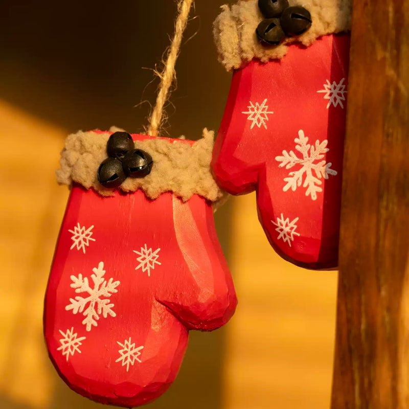 White snowflakes painted on two red wooden mittens with tan trim and black bell clusters