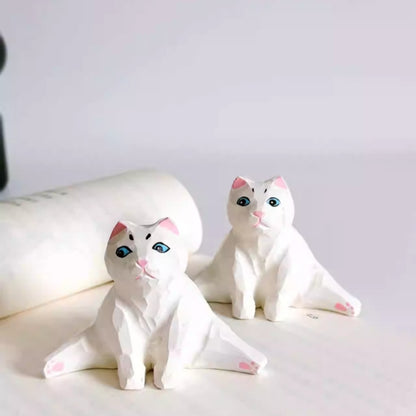 Pair of split pose cat figurines on display